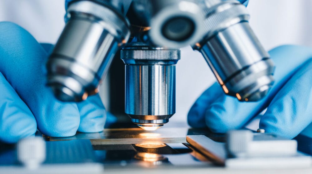 Close-up of a microscope lens over a glass slide